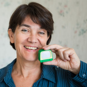 Christine Olderdissen hält ein grünes Spielzeugfernseherchen lächelnd vor ihr Gesicht